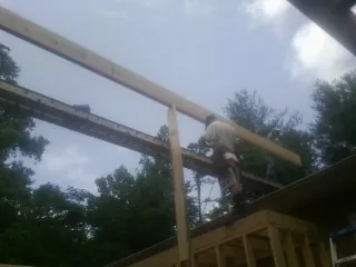 Carpenter setting a ridge beam over a new addition frame — Ice Dam Removal by Roofing Brothers in Hudsonville