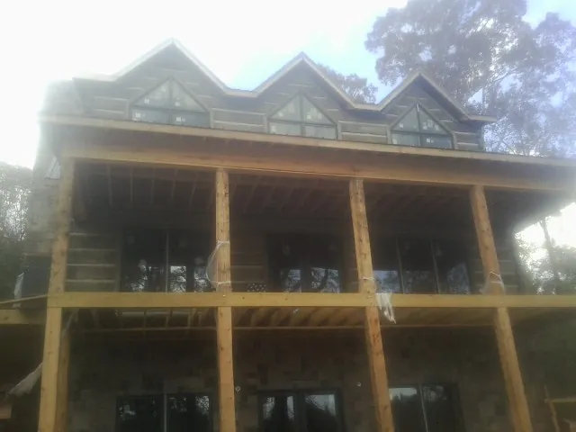 Dormers and porch framing on a large log home under construction — Roof Coating work by our crew in Hudsonville