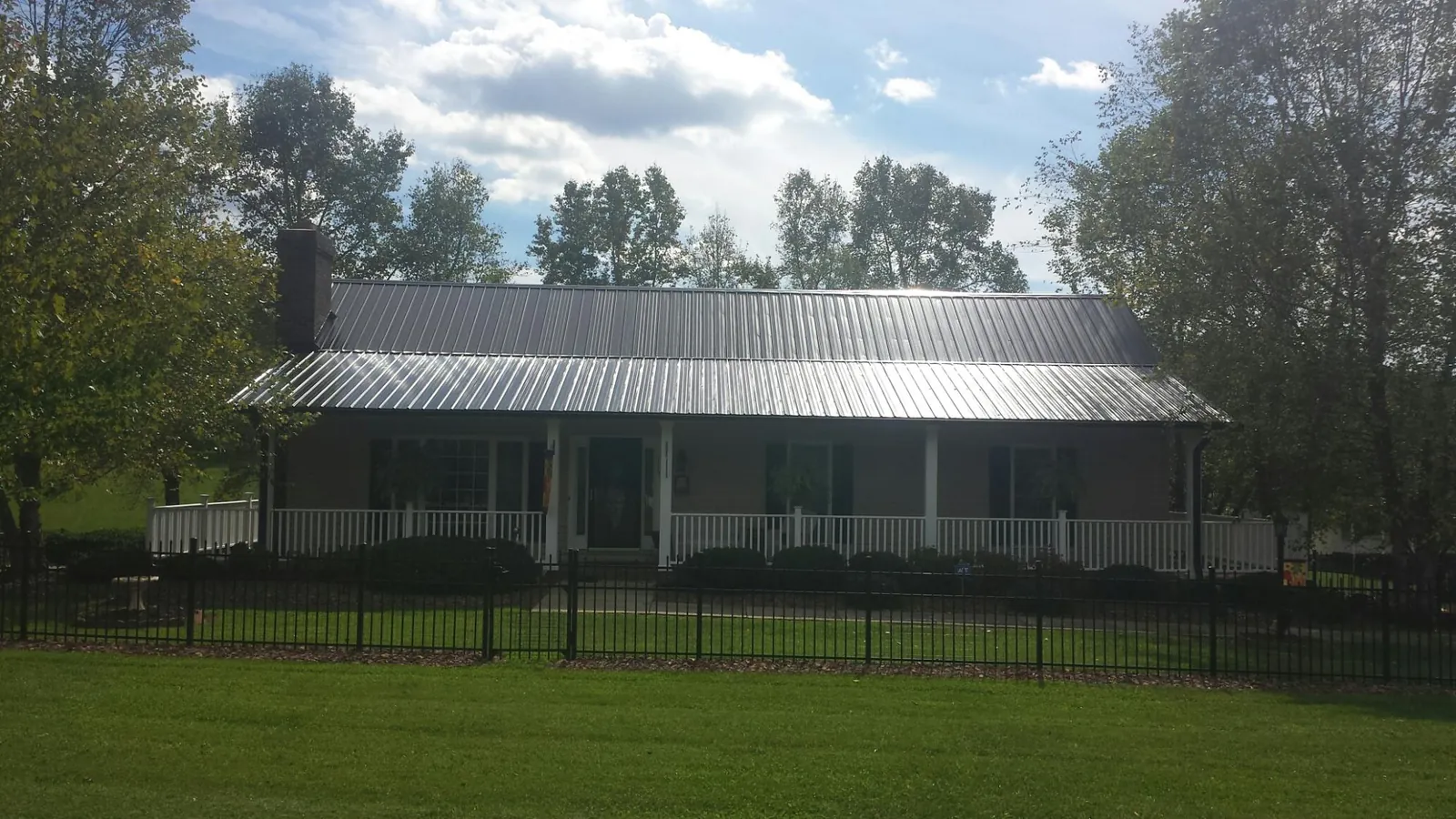 Gray metal roof on a brick ranch with a full width front porch — Gutter Guard Installation work by our crew in Hudsonville
