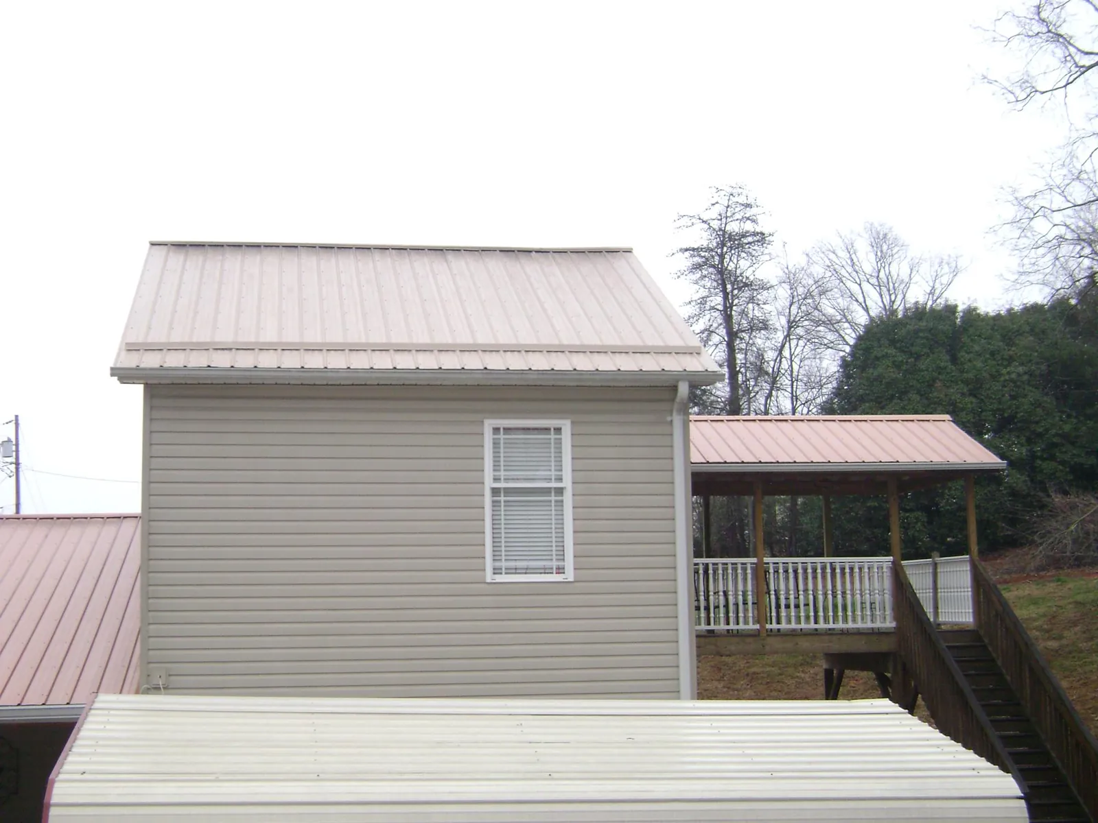 Tan metal roofs on a two story addition and attached porch, from a Roof Replacement job in Hudsonville