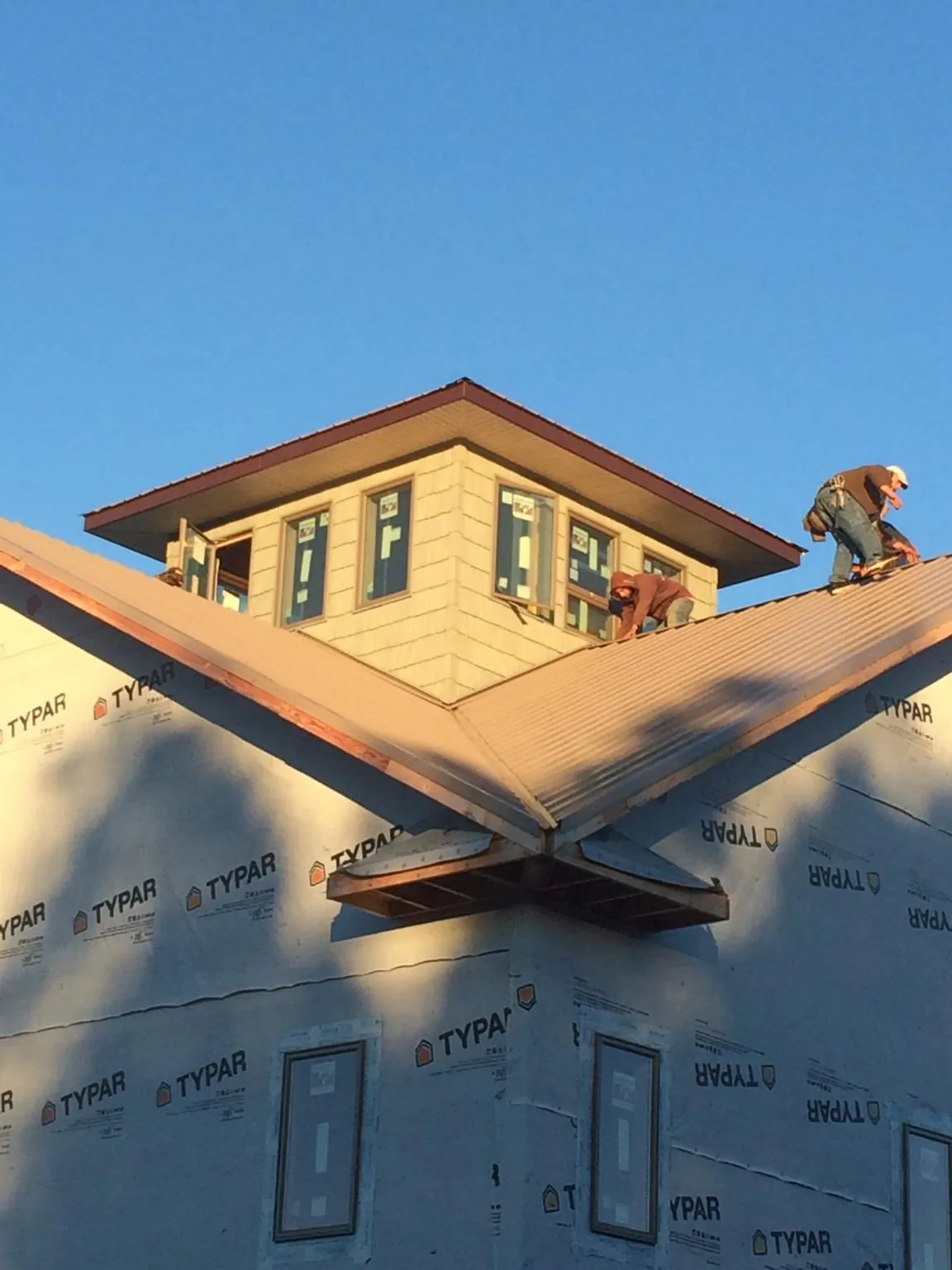 Roofers working around a rooftop cupola on a new metal roof at sunset — Roof Waterproofing in Hudsonville by Roofing Brothers